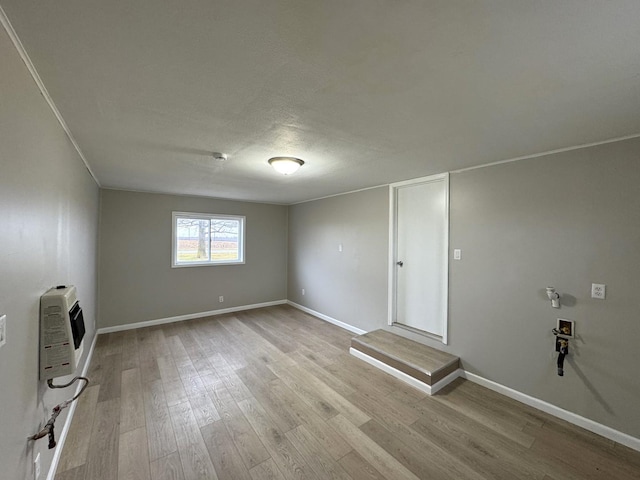 laundry room with a textured ceiling, light wood-type flooring, and heating unit