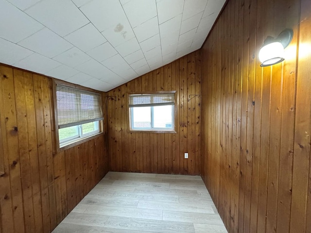 unfurnished room featuring hardwood / wood-style flooring, wood walls, and vaulted ceiling