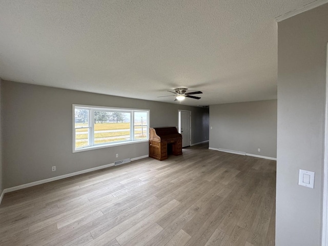 unfurnished living room with ceiling fan, light wood-type flooring, and a textured ceiling