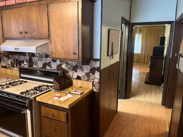 kitchen featuring white range with gas cooktop, light parquet floors, and exhaust hood