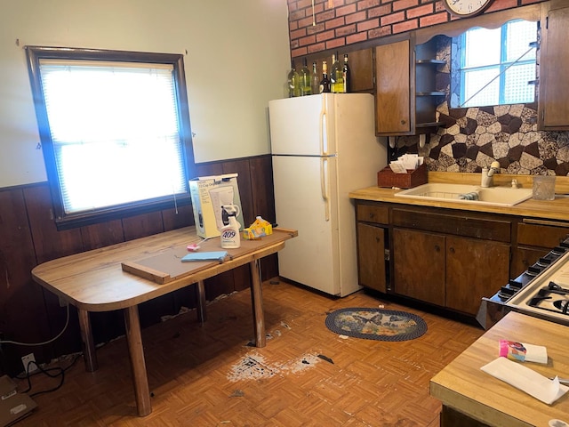 kitchen with dark brown cabinets, white fridge, sink, and light parquet floors