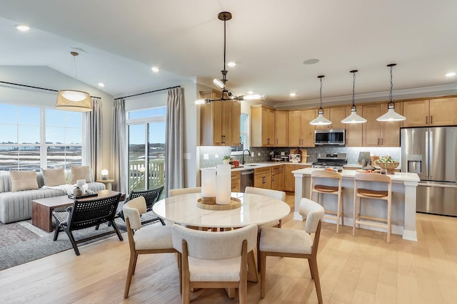 dining area with light hardwood / wood-style floors, lofted ceiling, and sink