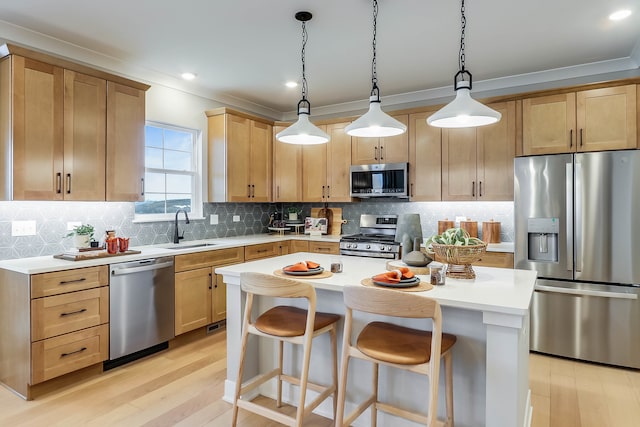 kitchen with appliances with stainless steel finishes, sink, light brown cabinets, a center island, and hanging light fixtures