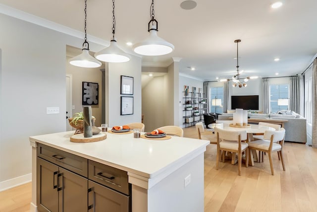 kitchen with pendant lighting, a center island, light hardwood / wood-style floors, and crown molding