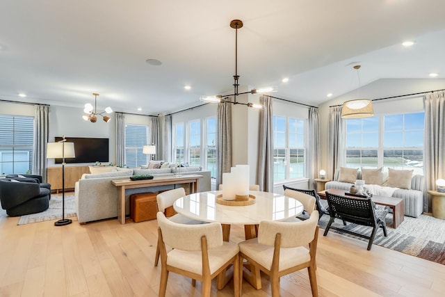 dining space featuring lofted ceiling, light wood-type flooring, a water view, and a notable chandelier