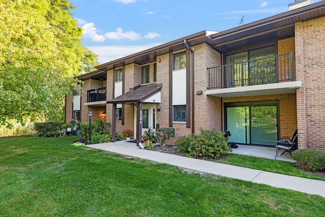 view of property featuring a patio area, a balcony, and a front yard