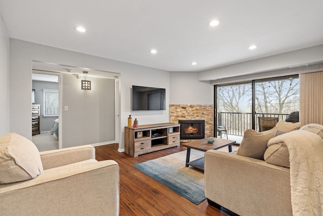 living room featuring a stone fireplace and dark hardwood / wood-style floors