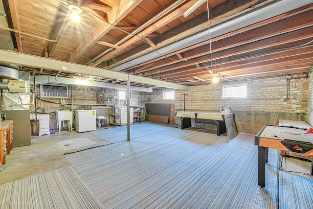 basement with sink, washer and dryer, and brick wall