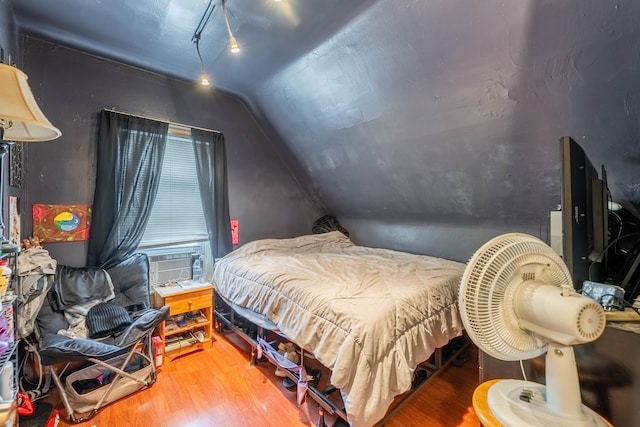 bedroom with hardwood / wood-style flooring, vaulted ceiling, and cooling unit