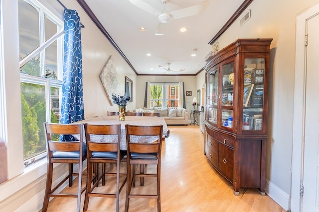 dining room with ceiling fan, ornamental molding, and light wood-type flooring