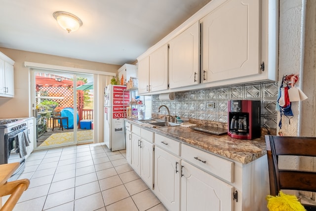 kitchen featuring sink, light tile patterned floors, stainless steel range with gas cooktop, backsplash, and white cabinets