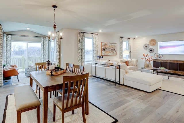 dining room featuring lofted ceiling, light hardwood / wood-style flooring, and a notable chandelier