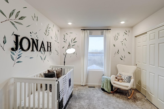 bedroom with a crib, carpet, and a closet