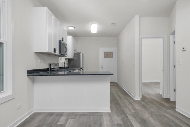 kitchen featuring white cabinetry, kitchen peninsula, stainless steel appliances, and light hardwood / wood-style flooring