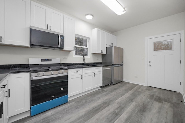 kitchen with white cabinets, sink, light wood-type flooring, and stainless steel appliances