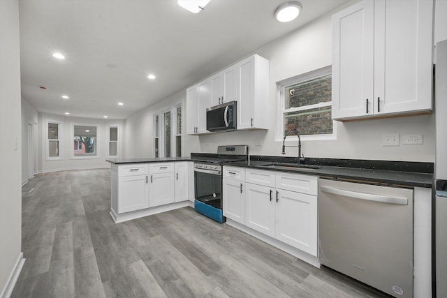 kitchen with sink, white cabinetry, stainless steel appliances, and light hardwood / wood-style flooring