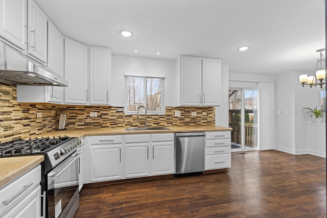 kitchen featuring decorative backsplash, stainless steel appliances, sink, pendant lighting, and white cabinets