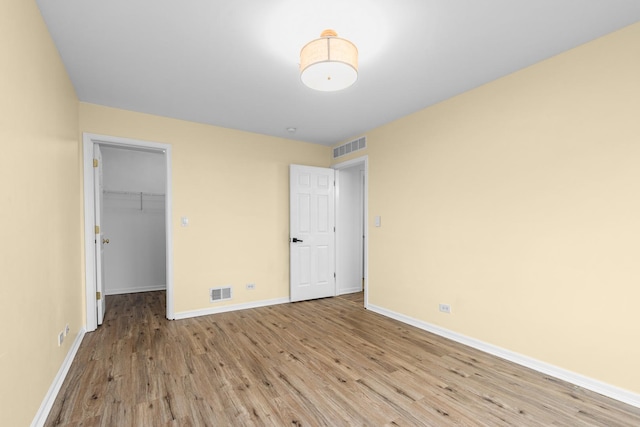 unfurnished bedroom featuring light wood-type flooring, a walk in closet, and a closet