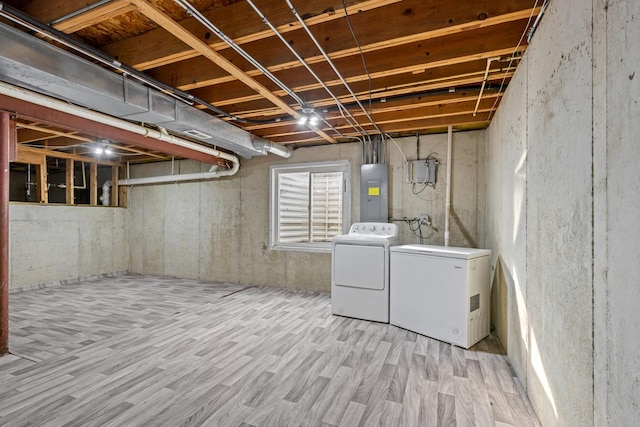 basement featuring independent washer and dryer, light wood-type flooring, electric panel, and fridge