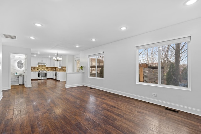 unfurnished living room with dark hardwood / wood-style flooring and an inviting chandelier