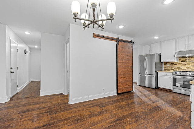 kitchen with a barn door, backsplash, pendant lighting, white cabinets, and appliances with stainless steel finishes