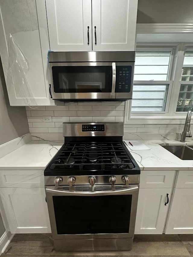 kitchen featuring light stone counters, white cabinets, and stainless steel appliances