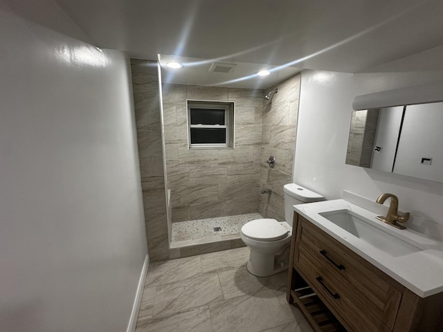 bathroom with a tile shower, vanity, and toilet