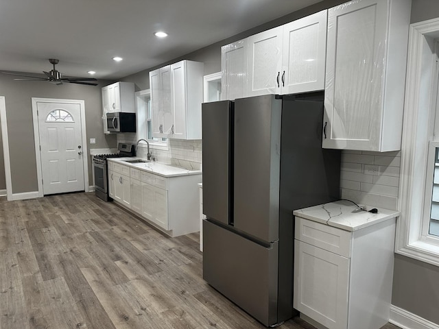 kitchen with tasteful backsplash, light stone countertops, white cabinets, and stainless steel appliances