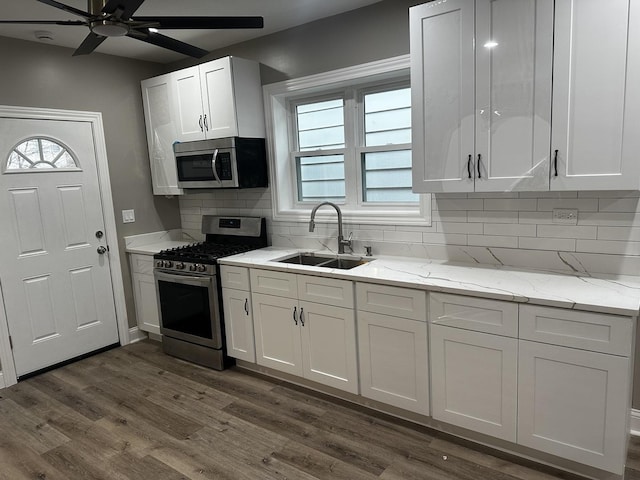 kitchen featuring backsplash, stainless steel appliances, dark wood-type flooring, sink, and white cabinets