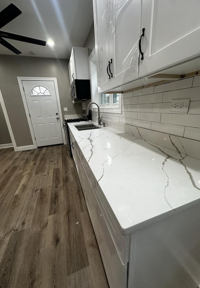 kitchen featuring white cabinets, sink, ceiling fan, tasteful backsplash, and light stone counters