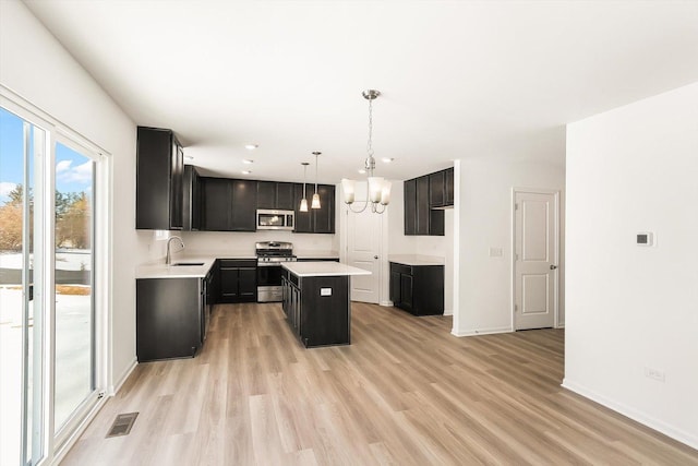 kitchen featuring visible vents, a kitchen island, appliances with stainless steel finishes, hanging light fixtures, and light countertops