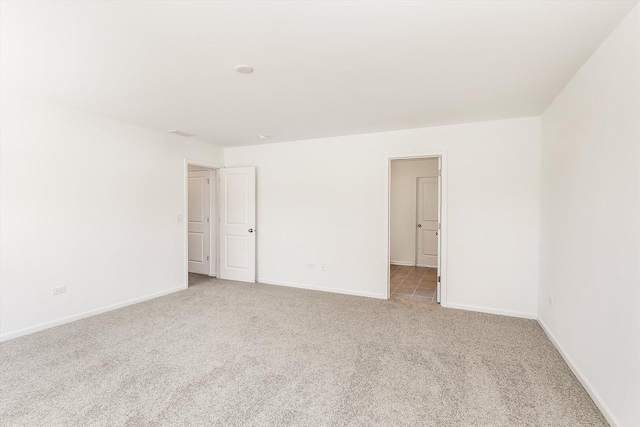 unfurnished room featuring light carpet and baseboards