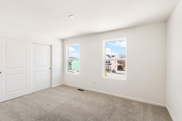 unfurnished bedroom featuring light carpet, a closet, visible vents, and baseboards