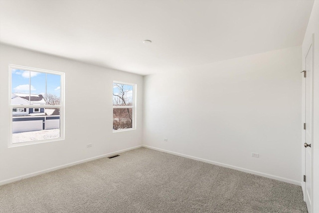 carpeted spare room featuring baseboards and visible vents