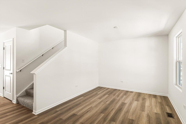 unfurnished room with dark wood-style floors, stairway, visible vents, and baseboards