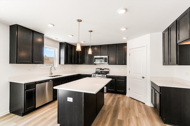 kitchen featuring a center island, stainless steel appliances, light countertops, hanging light fixtures, and a sink