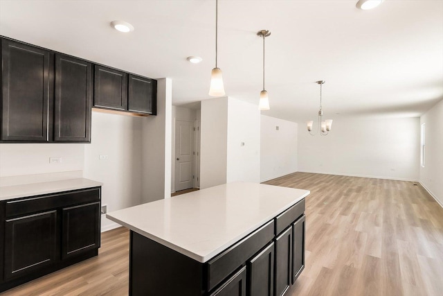 kitchen with light wood finished floors, open floor plan, decorative light fixtures, a center island, and light countertops