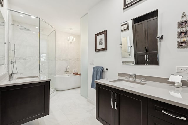 full bath featuring marble finish floor, a freestanding bath, two vanities, and a sink