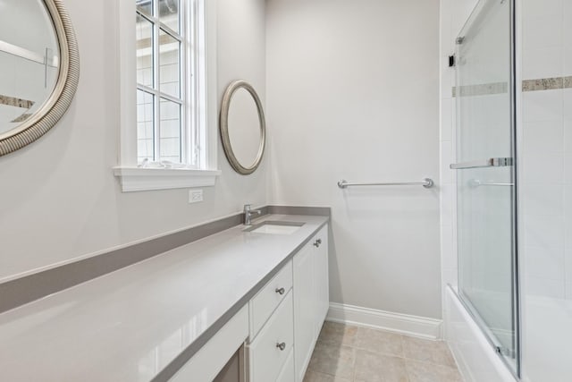 bathroom featuring tile patterned floors, enclosed tub / shower combo, baseboards, and vanity