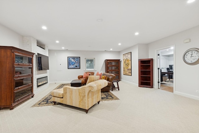 living area featuring a large fireplace, baseboards, light carpet, and recessed lighting