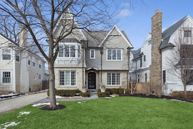 view of front of home with a front yard, stone siding, and fence