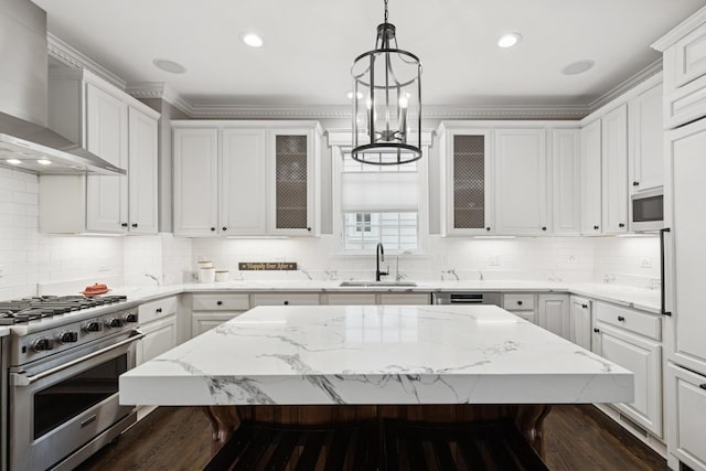 kitchen featuring wall chimney exhaust hood, a breakfast bar area, and glass insert cabinets