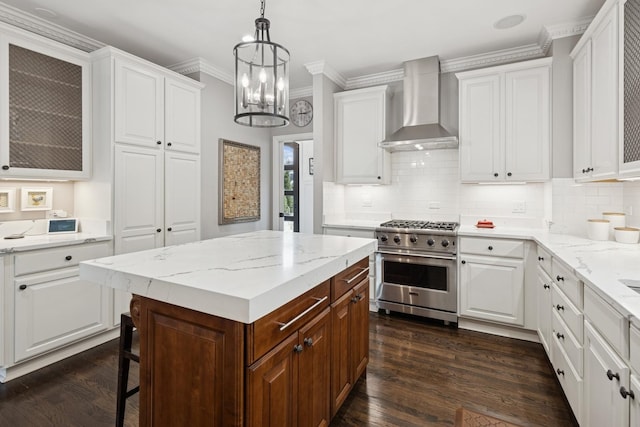 kitchen featuring wall chimney range hood, high end stainless steel range, glass insert cabinets, and white cabinets