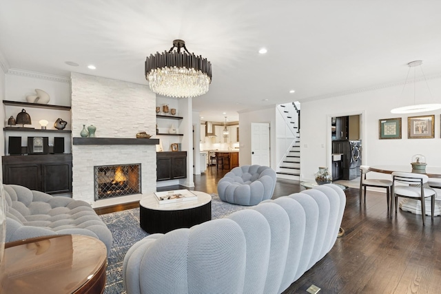 living area with dark wood finished floors, stairs, a stone fireplace, a notable chandelier, and recessed lighting