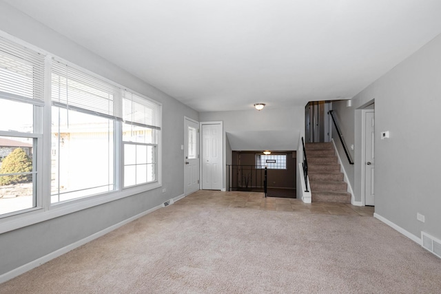 unfurnished living room featuring light colored carpet and plenty of natural light