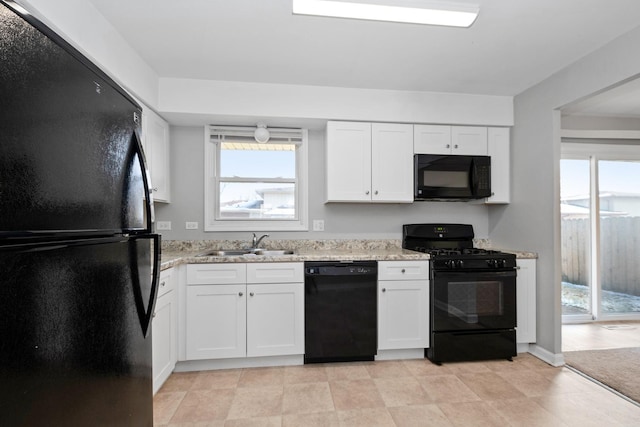 kitchen with sink, light stone counters, white cabinetry, and black appliances