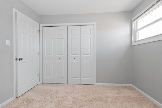 unfurnished bedroom with light colored carpet and a closet