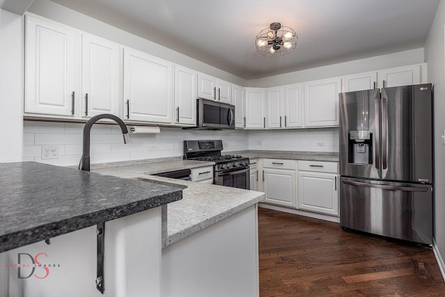 kitchen featuring kitchen peninsula, appliances with stainless steel finishes, tasteful backsplash, dark hardwood / wood-style flooring, and white cabinetry