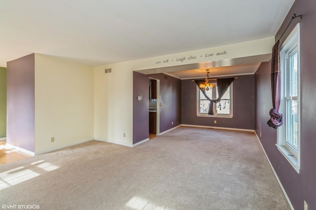 spare room featuring carpet flooring and a notable chandelier