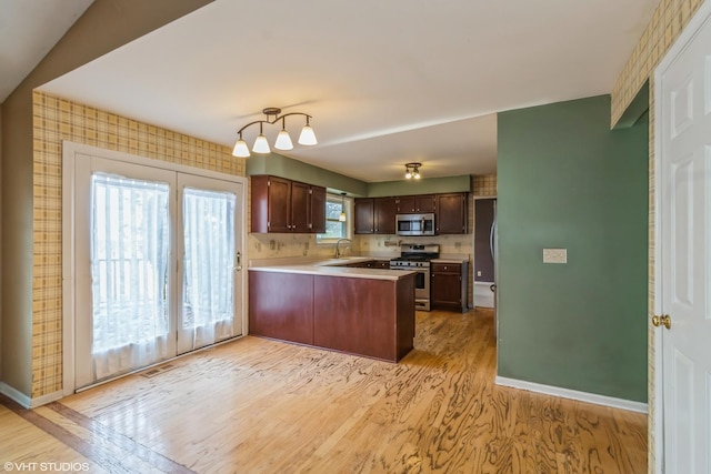 kitchen featuring dark brown cabinetry, sink, light hardwood / wood-style flooring, appliances with stainless steel finishes, and kitchen peninsula